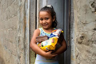 7-year-old Merari holds a food basket her family recently received from her Compassion center