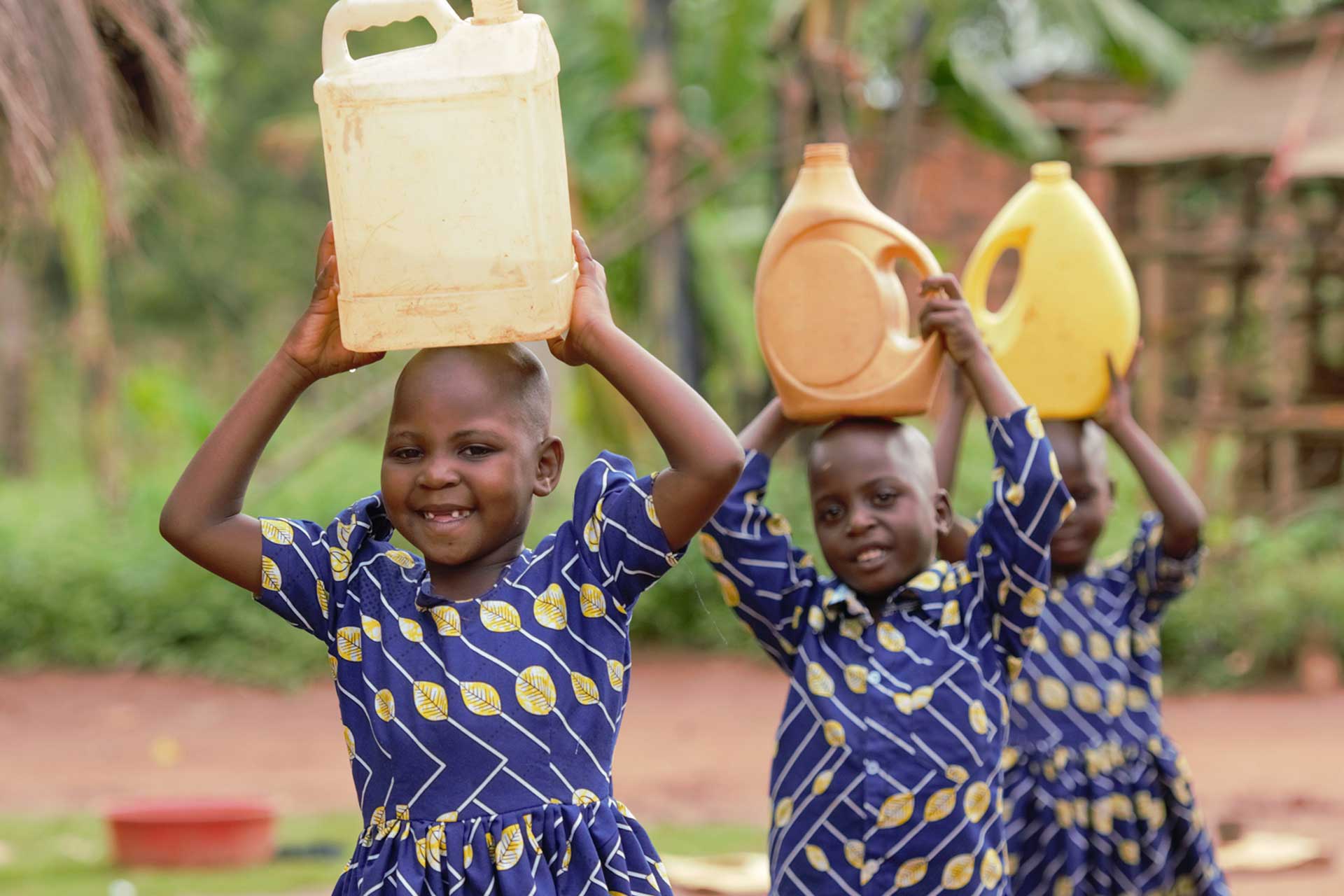 triplets Grace, Samuel and Patience carry water