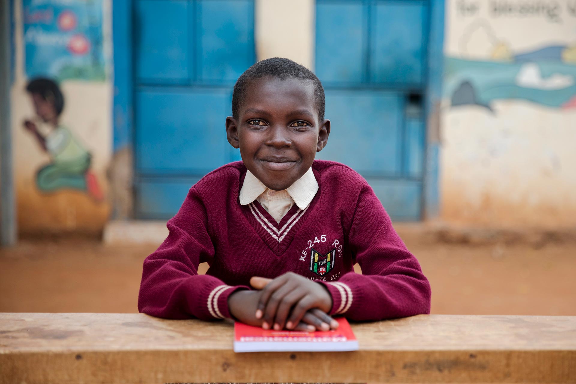 an African boy sits in front of his Compassion center