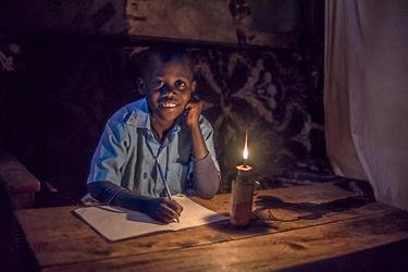 Bravin does his homework by the light of a kerosene lamp