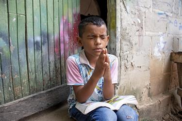 Luis prays and reads his Bible in front of his house