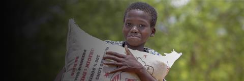 A child holds a bag of rice with a green background