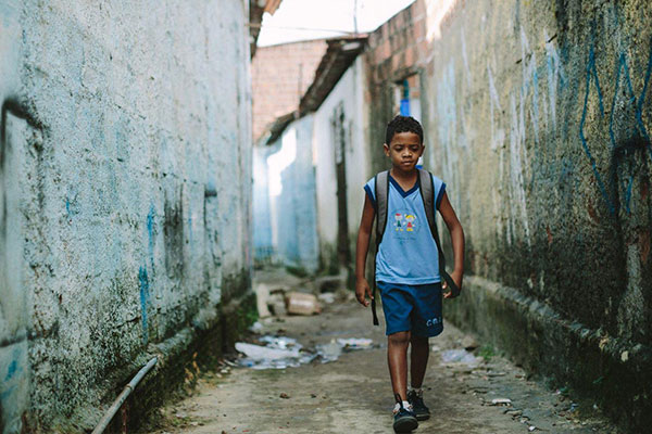 A boy walking to school down an alleyway