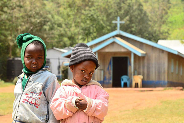 Two young children standing outside a local church