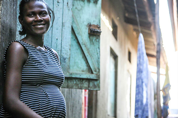 A pregnant woman standing outside her home