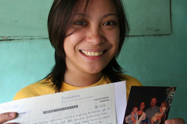 A girl holding up her sponsor letter and photo