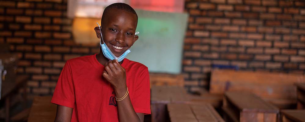 Child in Rwanda putting on mask