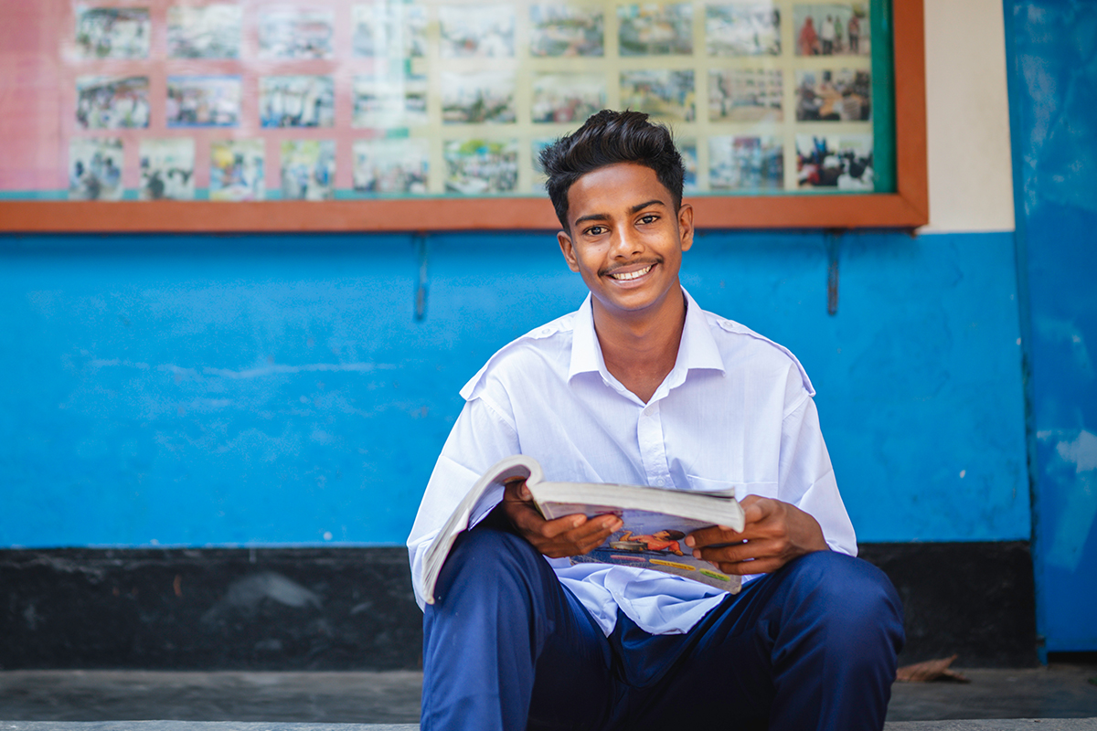 Shanto sits outside at his school