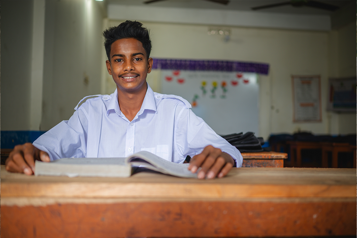 Shanto sits at a desk at his school