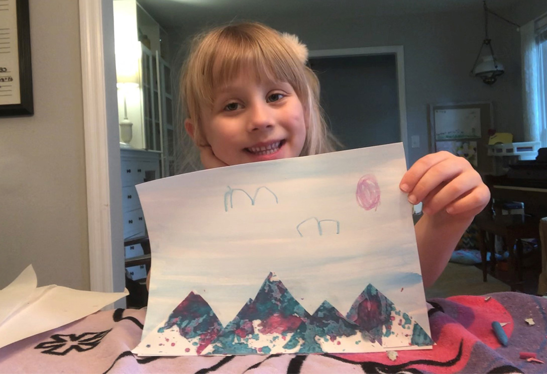 Evie holds up her artwork