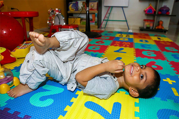 A young boy from Colombia with special needs lays on the floor