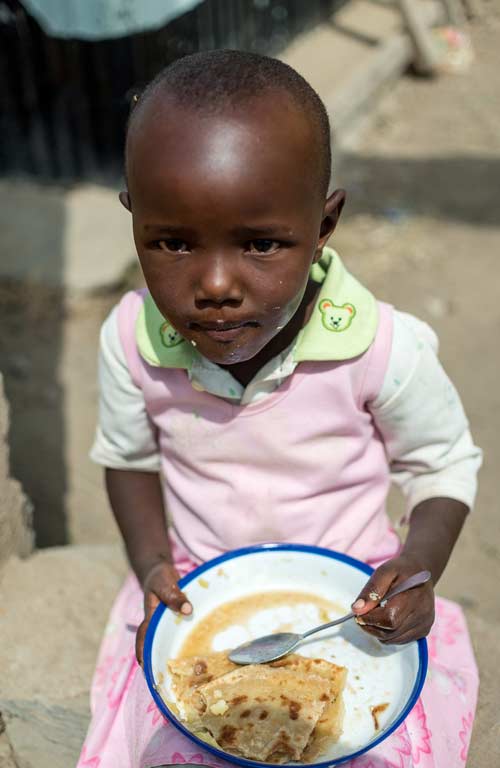 A young girl eating her meal in Kenya