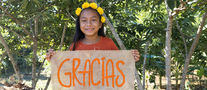 a girl hold a sign that says gracias