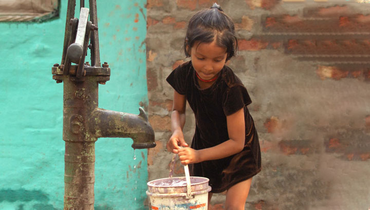 A girl filling her bucket with safe water from the local pump
