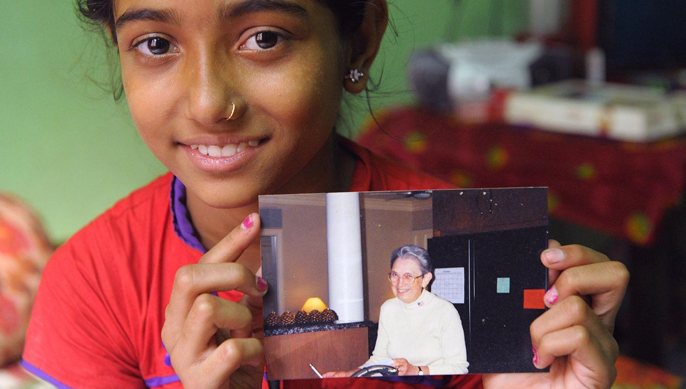 An Indian girl holding a photo of her sponsor