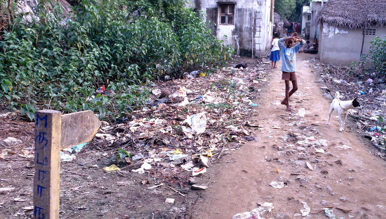 A boy walking by a dog on a path with garbage
