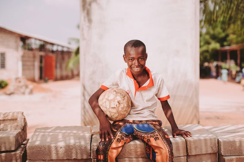 A teen boy holding a soccer ball