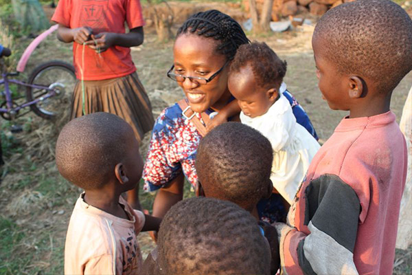 A woman smiles with a group of children