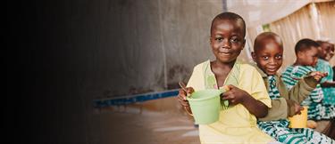 Two boys with cups smiling at the camera.