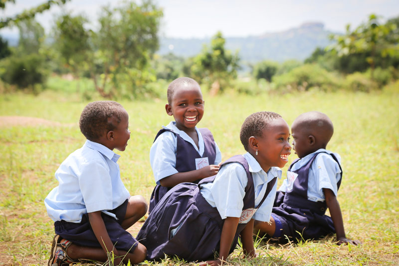 Children sit in the grass laughing and playing