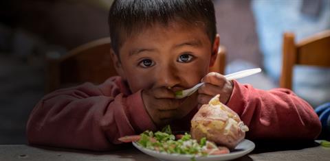 A young boy taking a bite of food