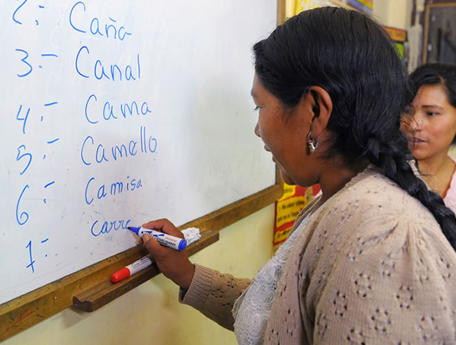 A mother practices writing Spanish on a whiteboard