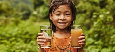 girl holds a glass of clean water and a glass of dirty water