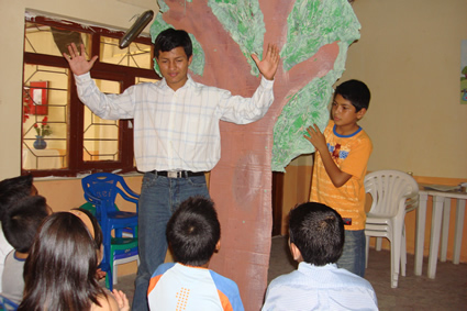 a man stands in front of a group of children with his arms raised