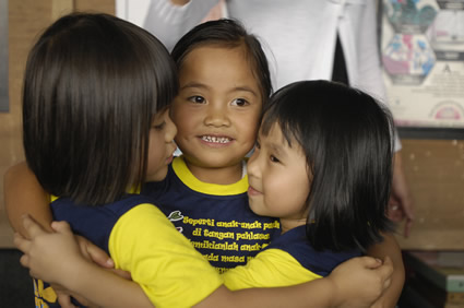 three young girls hugging one another