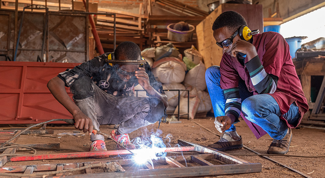 Emmanuel instructing a student in welding