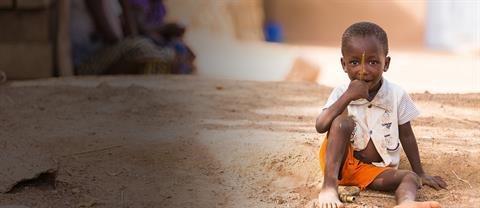 A young boy sits on a street in a poor country