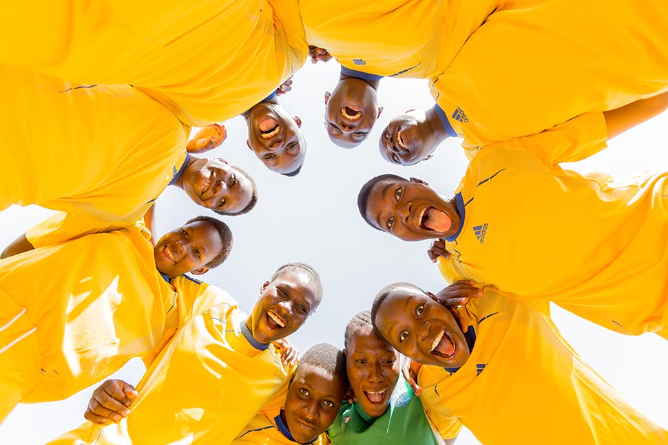 A group of boys wearing yellow shirts stand in a circle