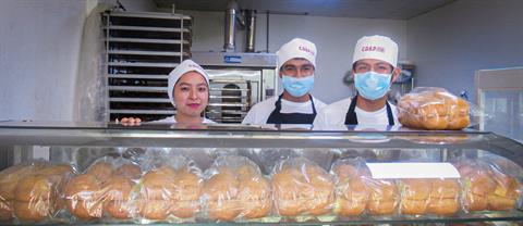 Three people smile in a bakery