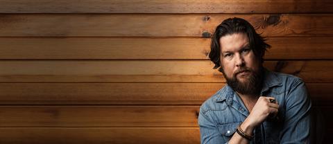 Zach Williams stands in front of a wooden wall