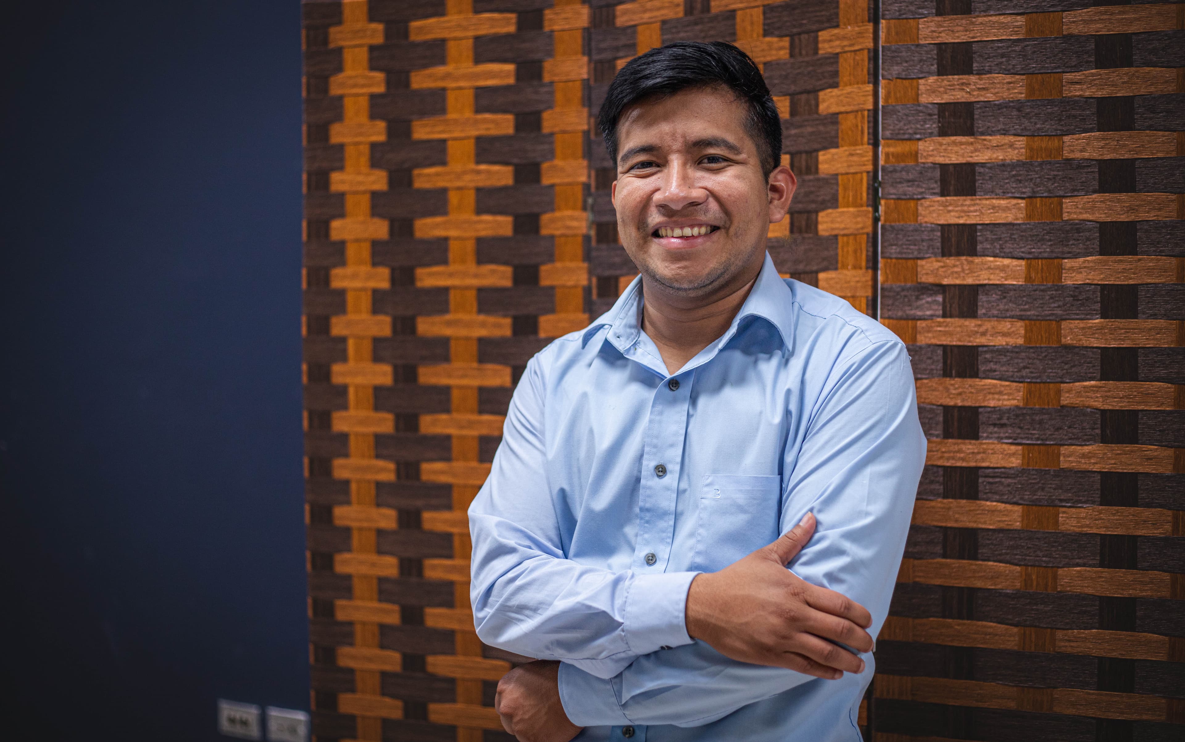 A man stands with his arms crossed as he smiles at the camera.