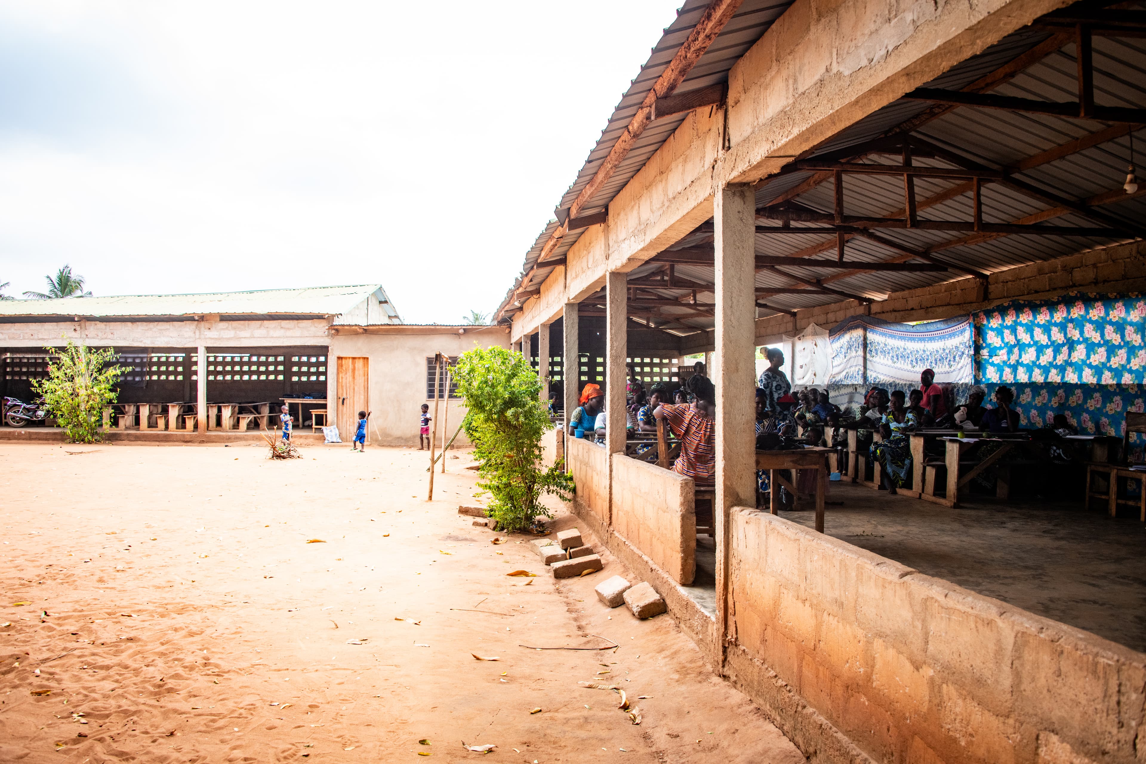 Women gather at wooden desks in an outside classroom at a Compassion center.