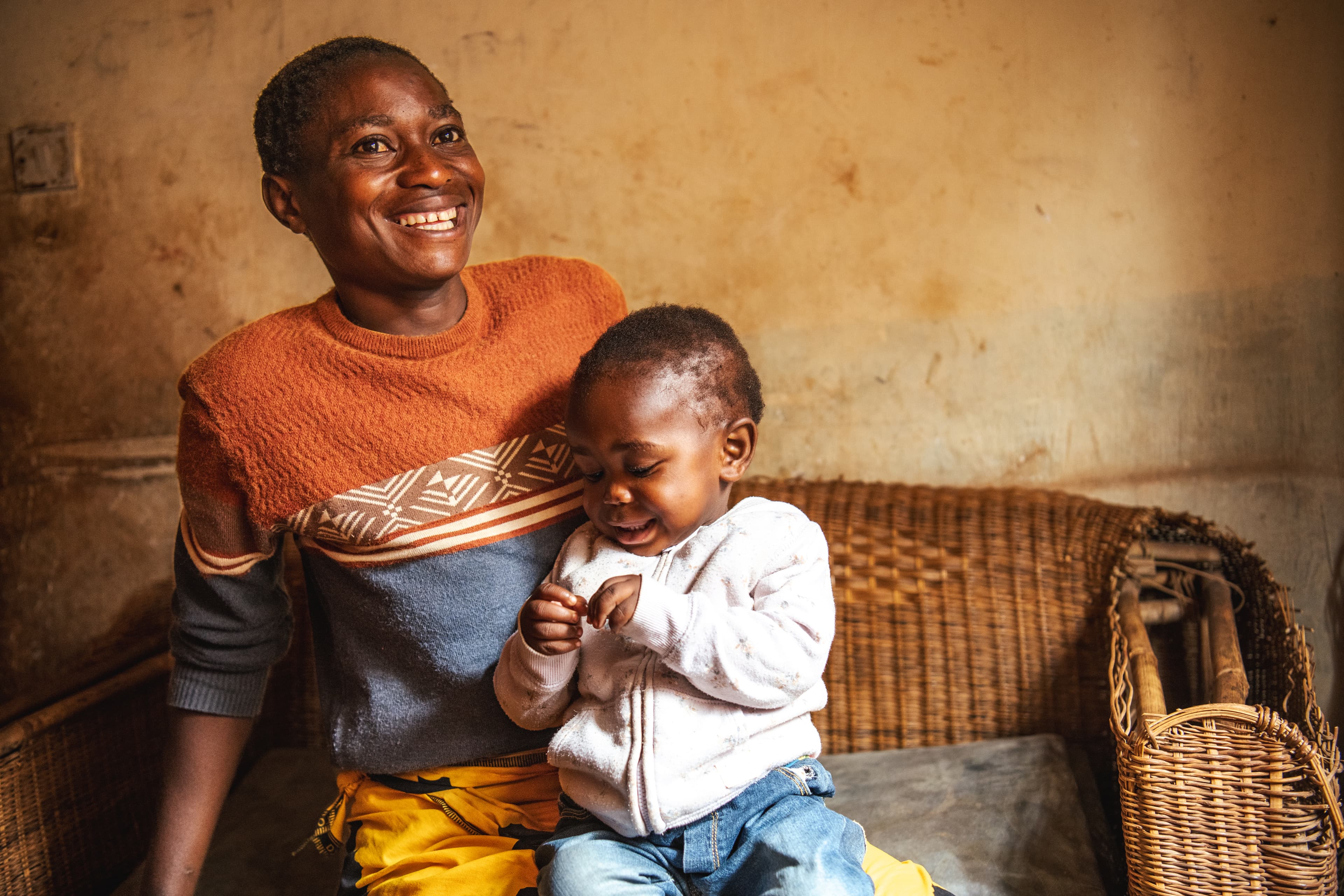 A mother is sitting with her child on her lap, both smiling.