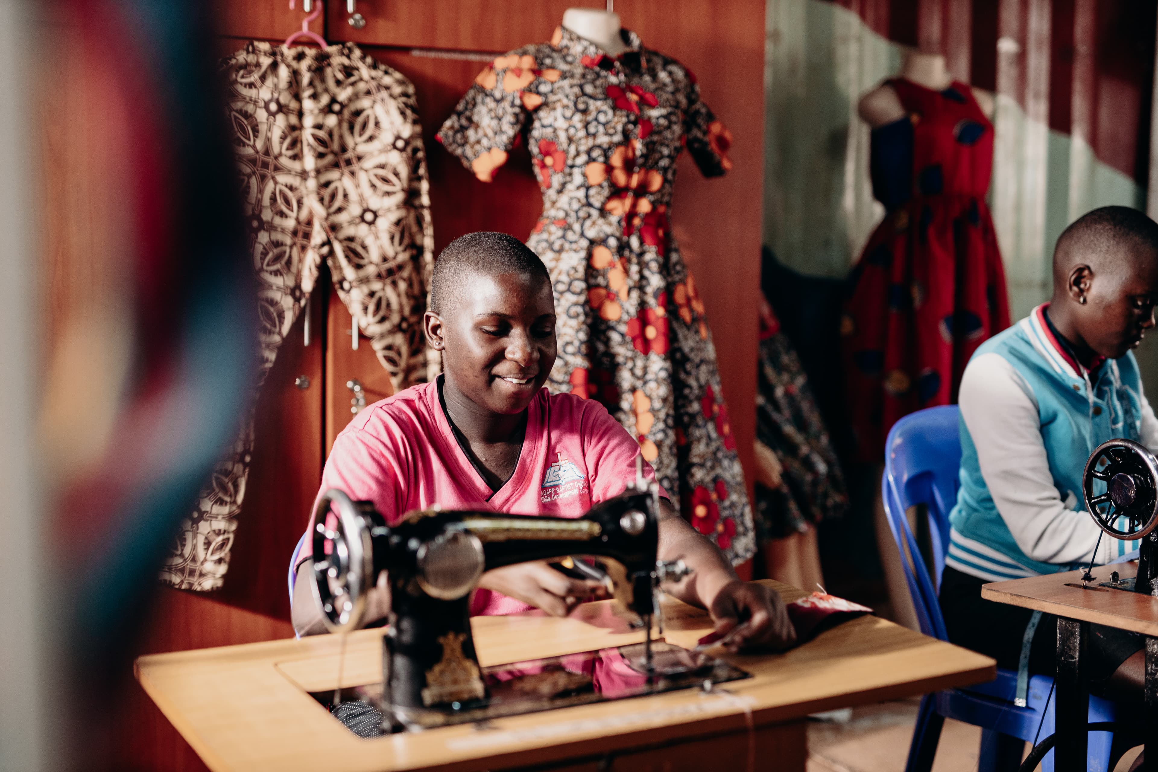 Teenaged girl sits at a sewing machine with fabric.