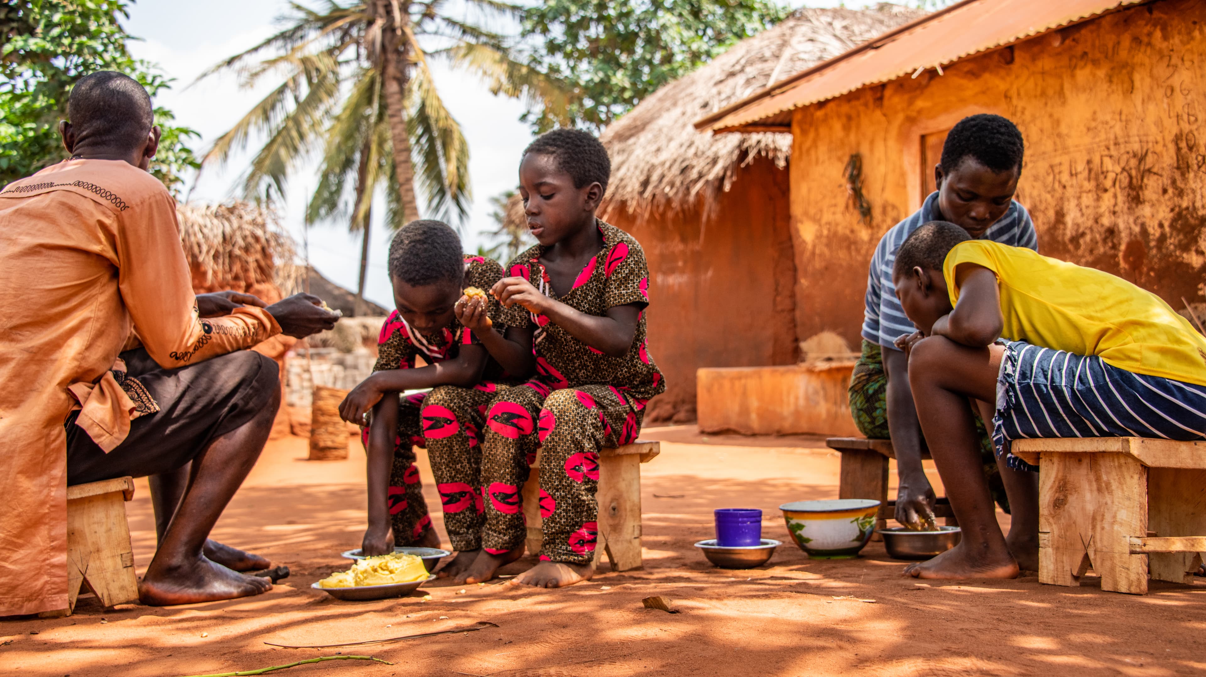 Young girl is sitting outside her home with her family eating lunch.