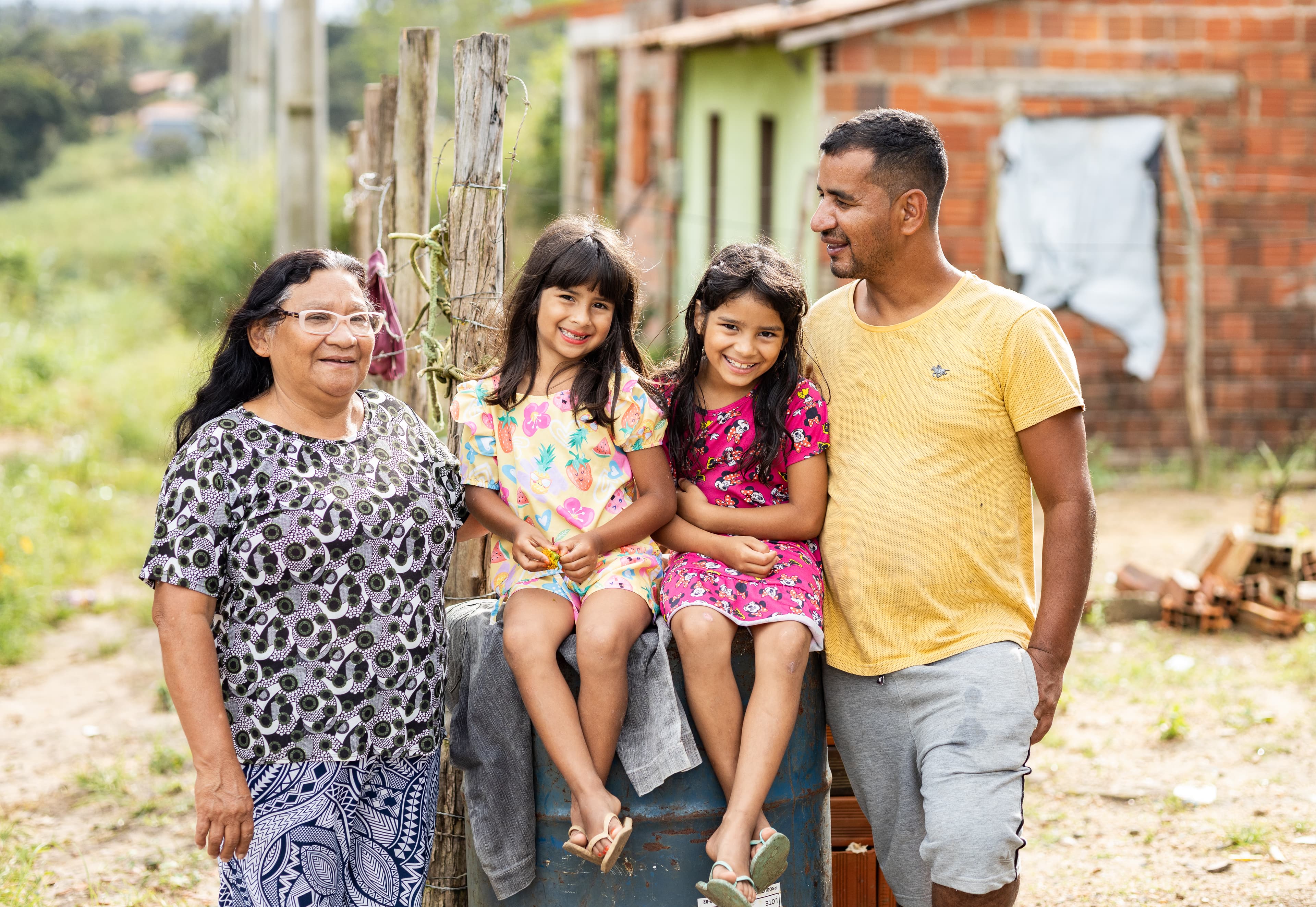 Two young girls smile next to their father and grandmother.