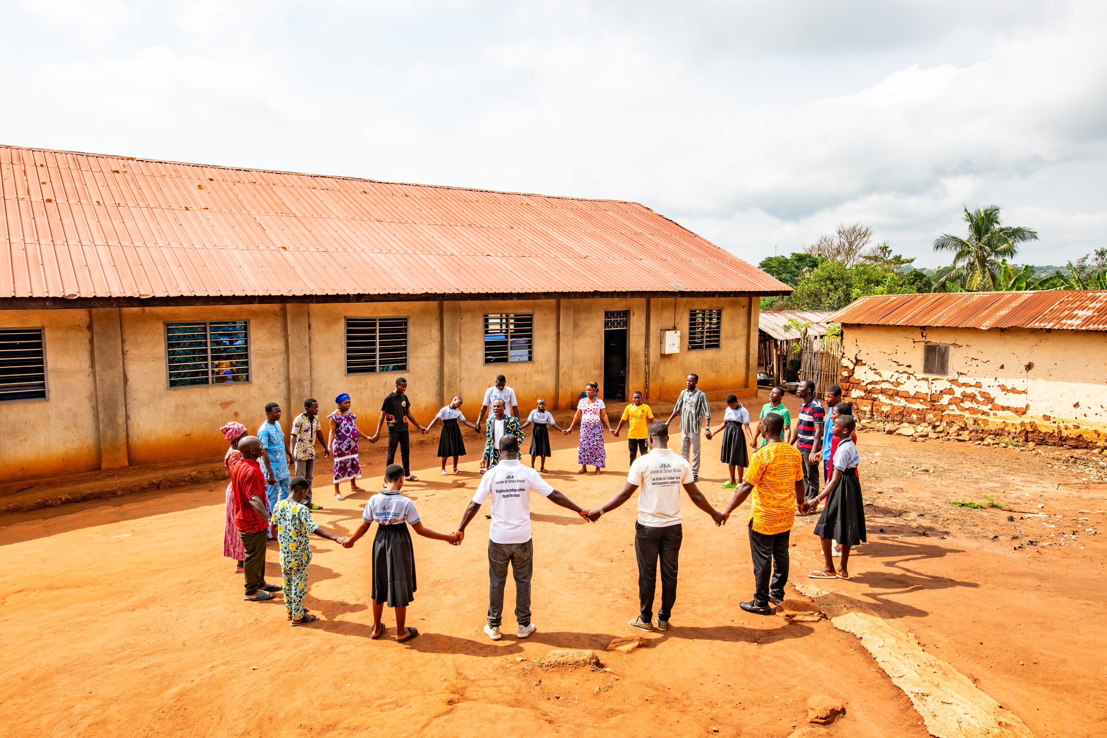 A group of people hold hands in a large circle while praying outside of a church.