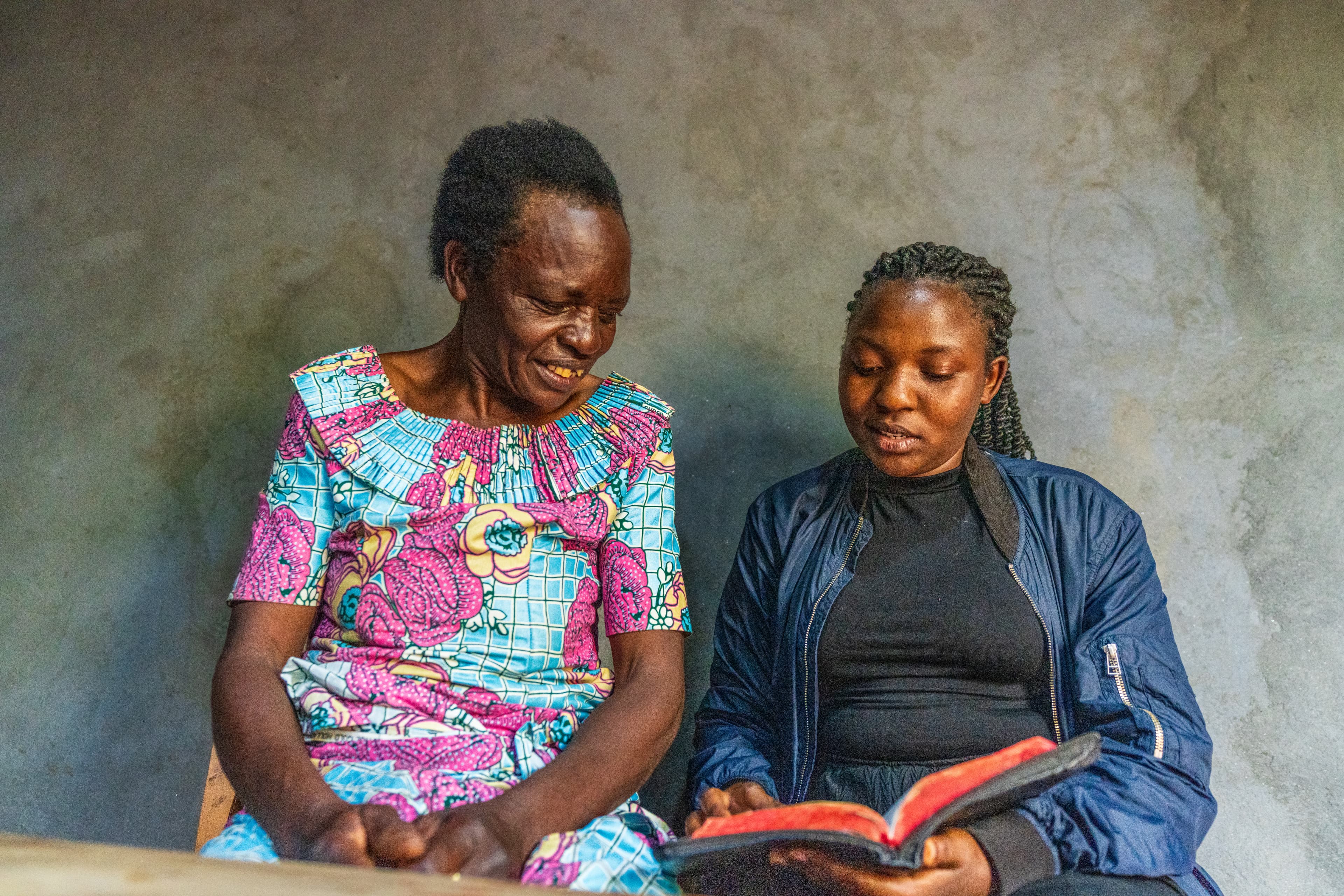 A young woman and her mother are reading the bible and discussing scriptures together.