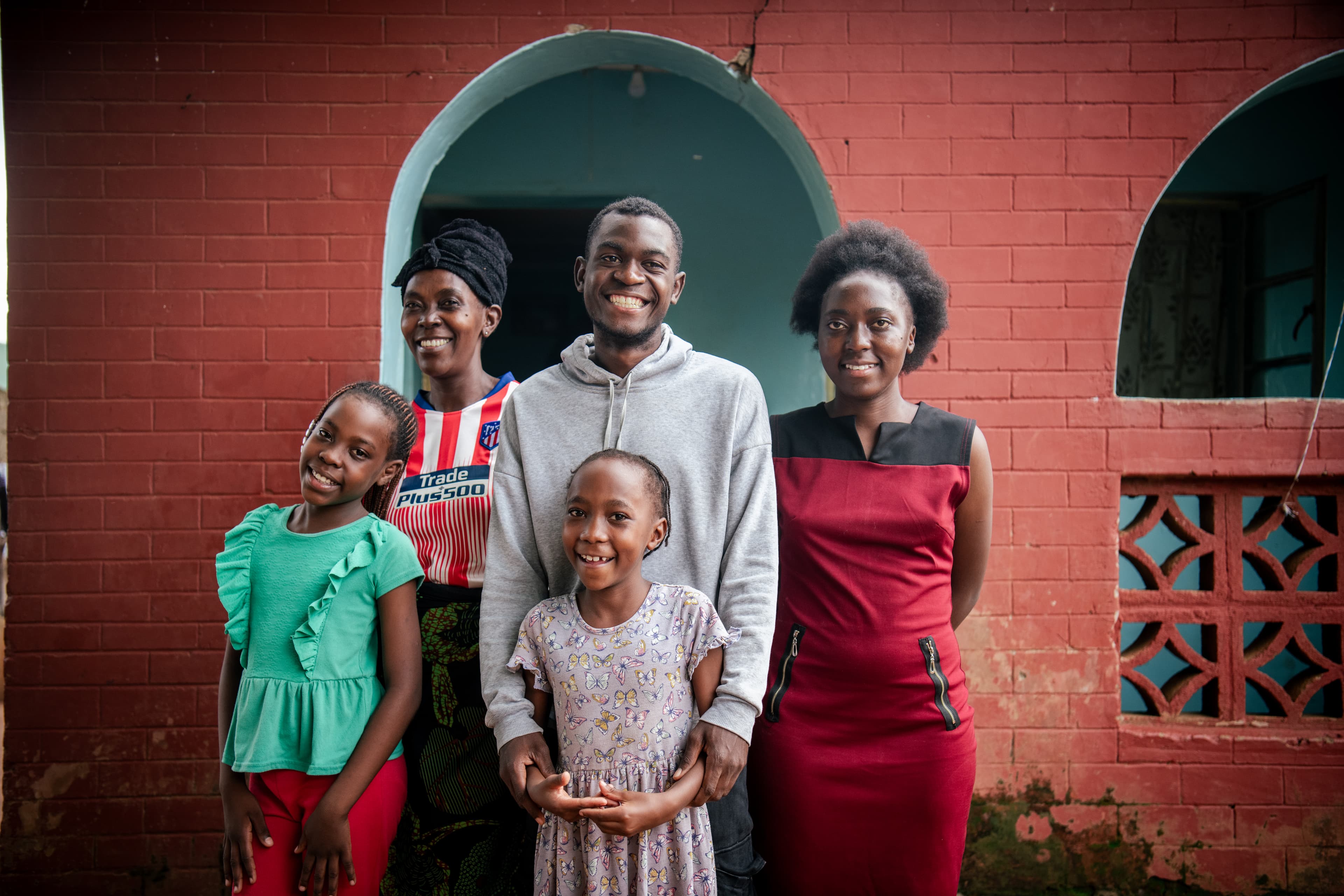 A family stands together smiling at the camera.