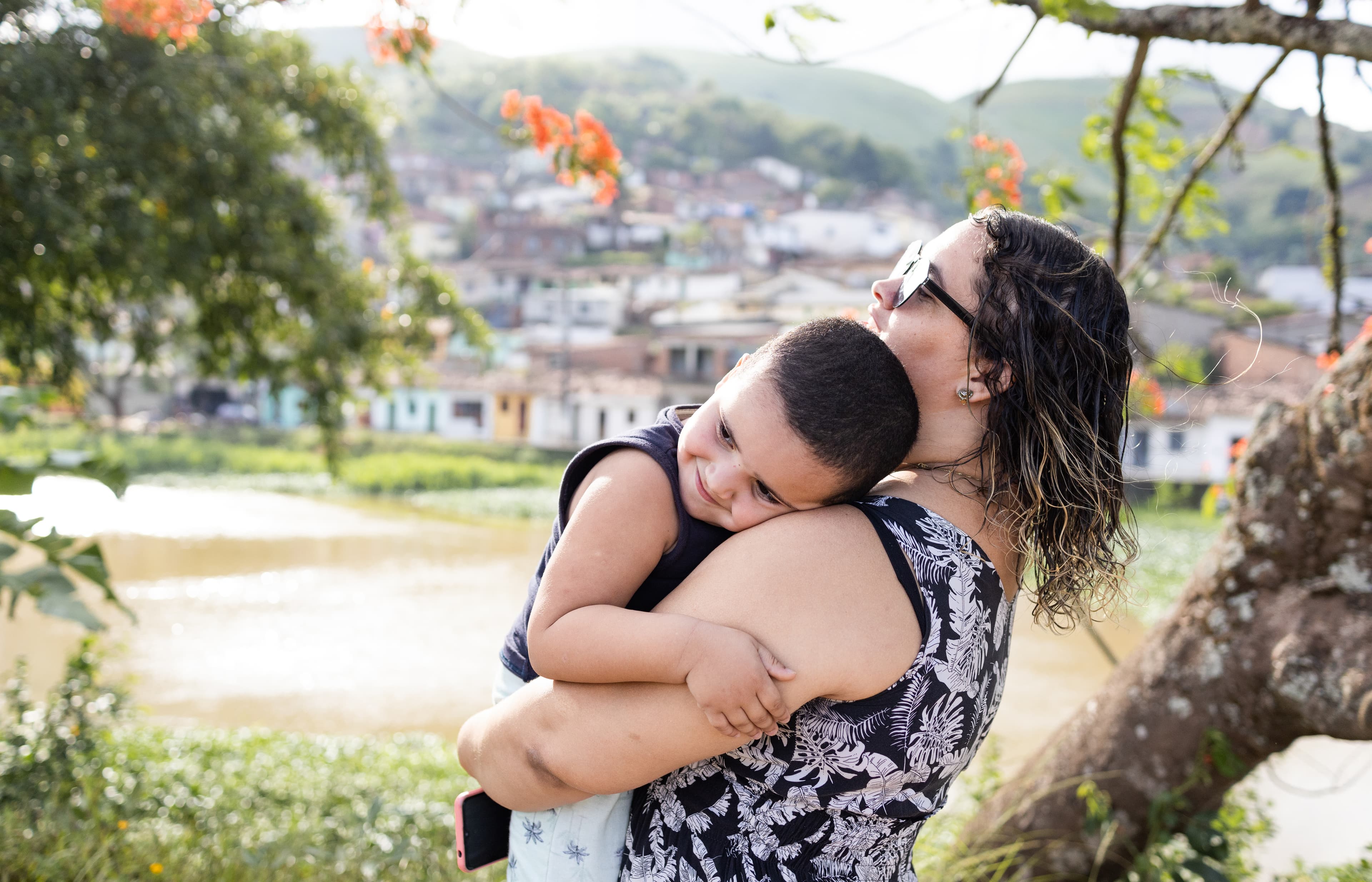 A young woman wearing a patterned dress holds a toddler boy in her arms.