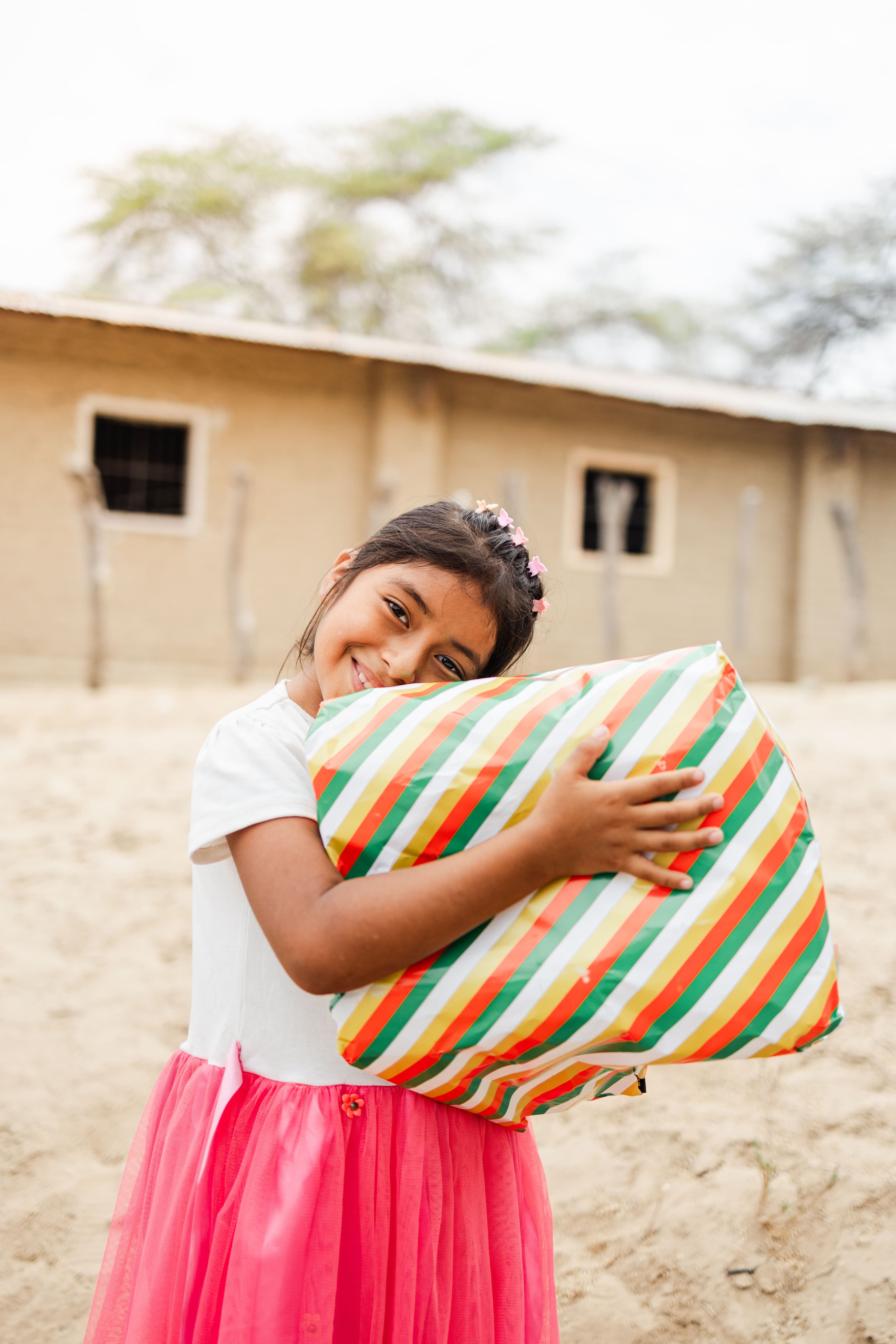 A young girl is smiling and holding a gift.