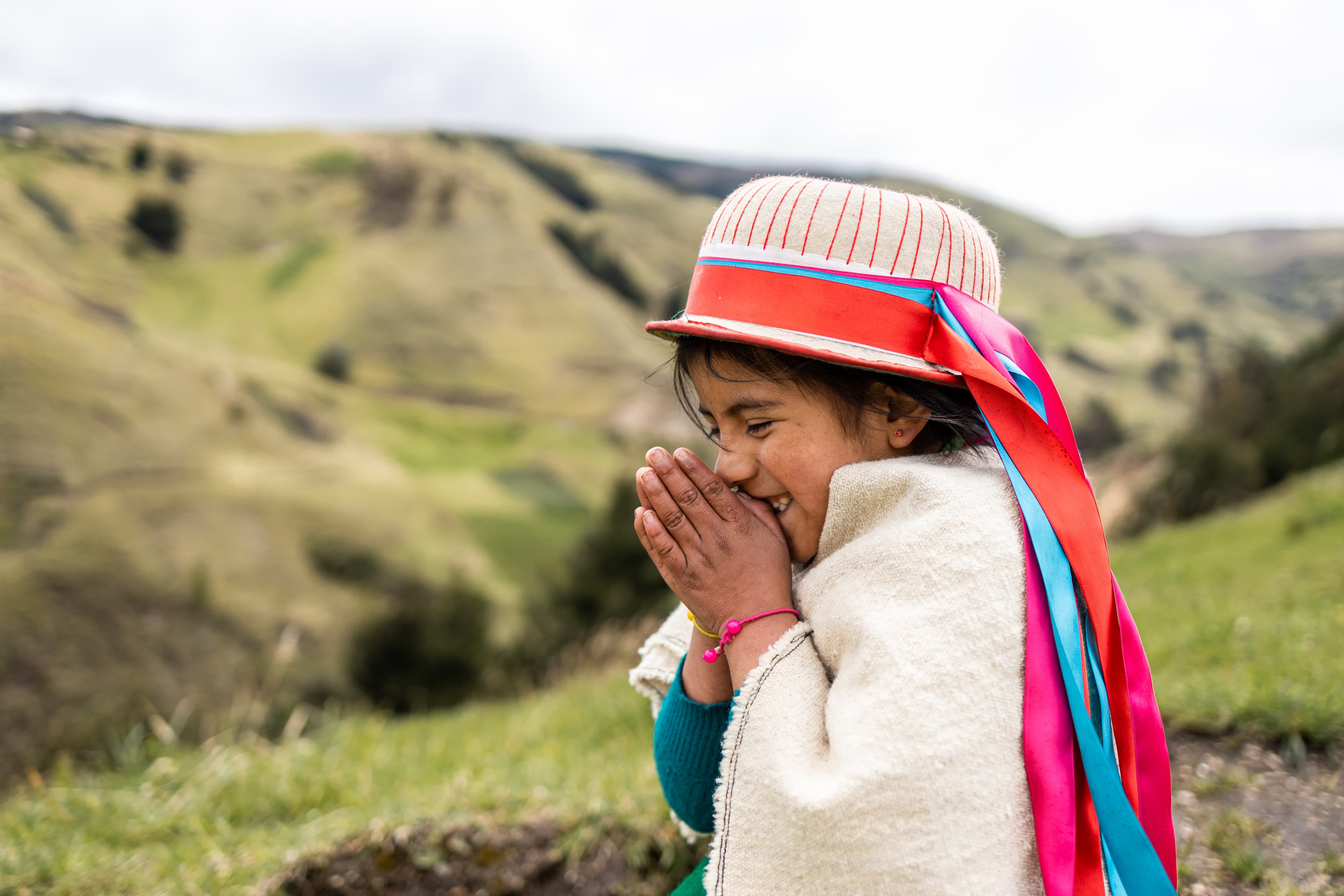 A young girl is standing and praying with a smile on her face