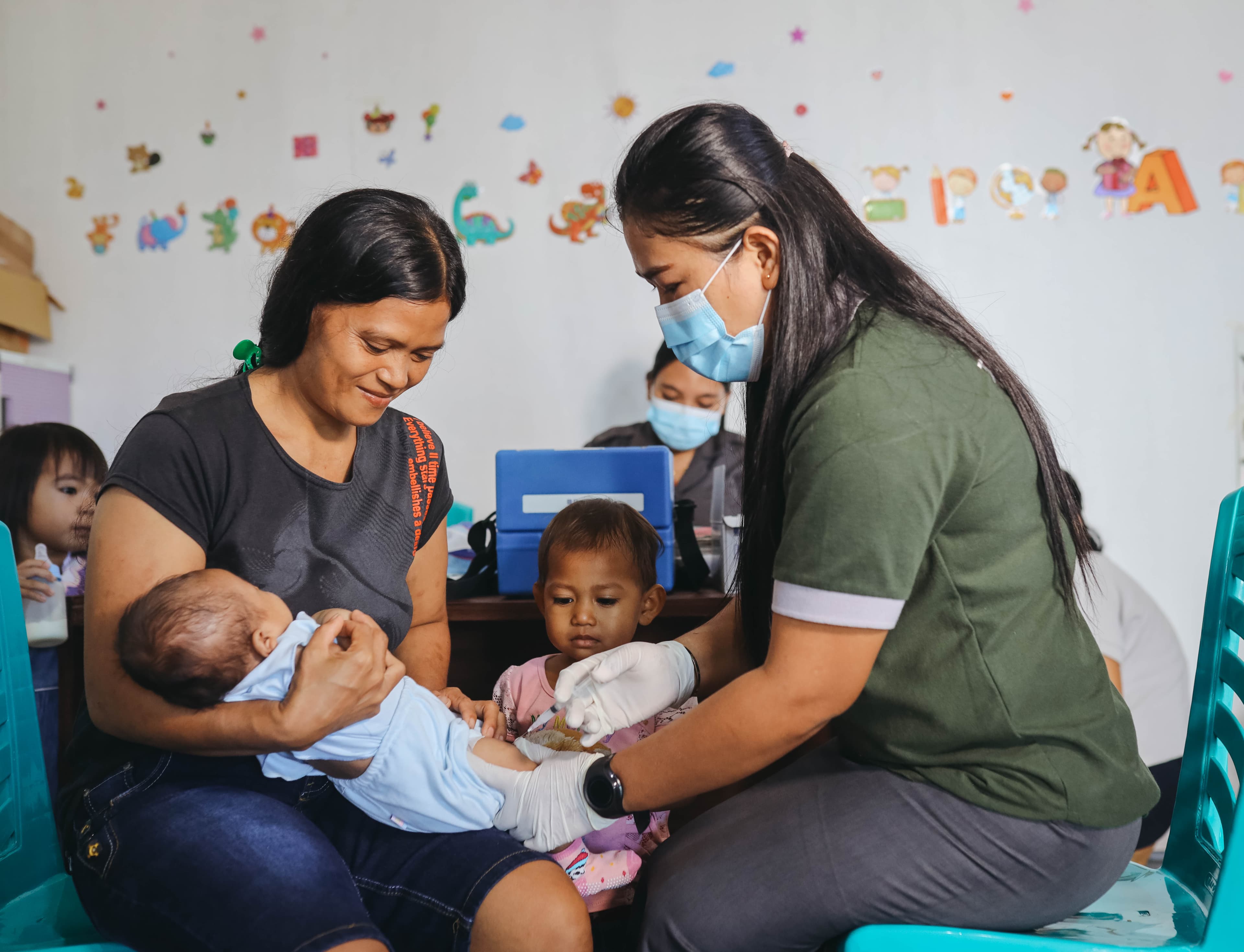 An Indonesian mother holds her baby girl as the child receives an immunization from a health care worker.
