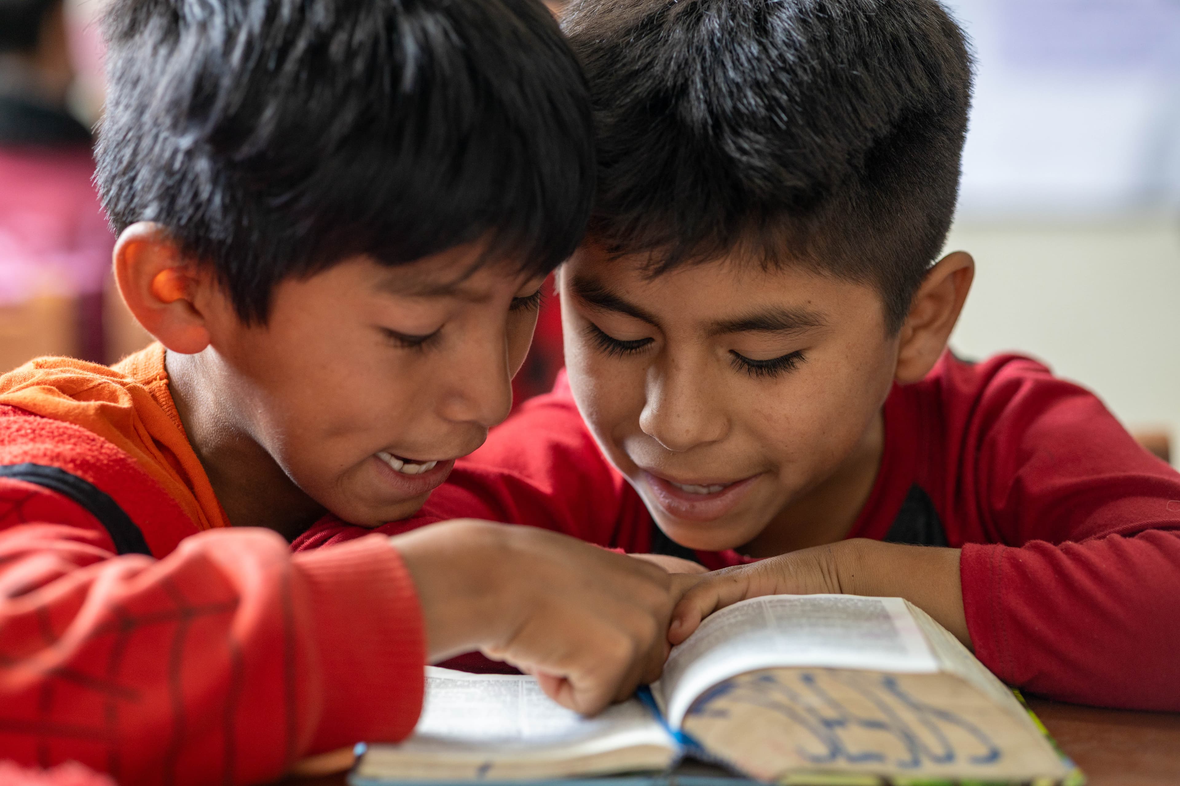 Two Bolivian boys sit and read a Bible together.