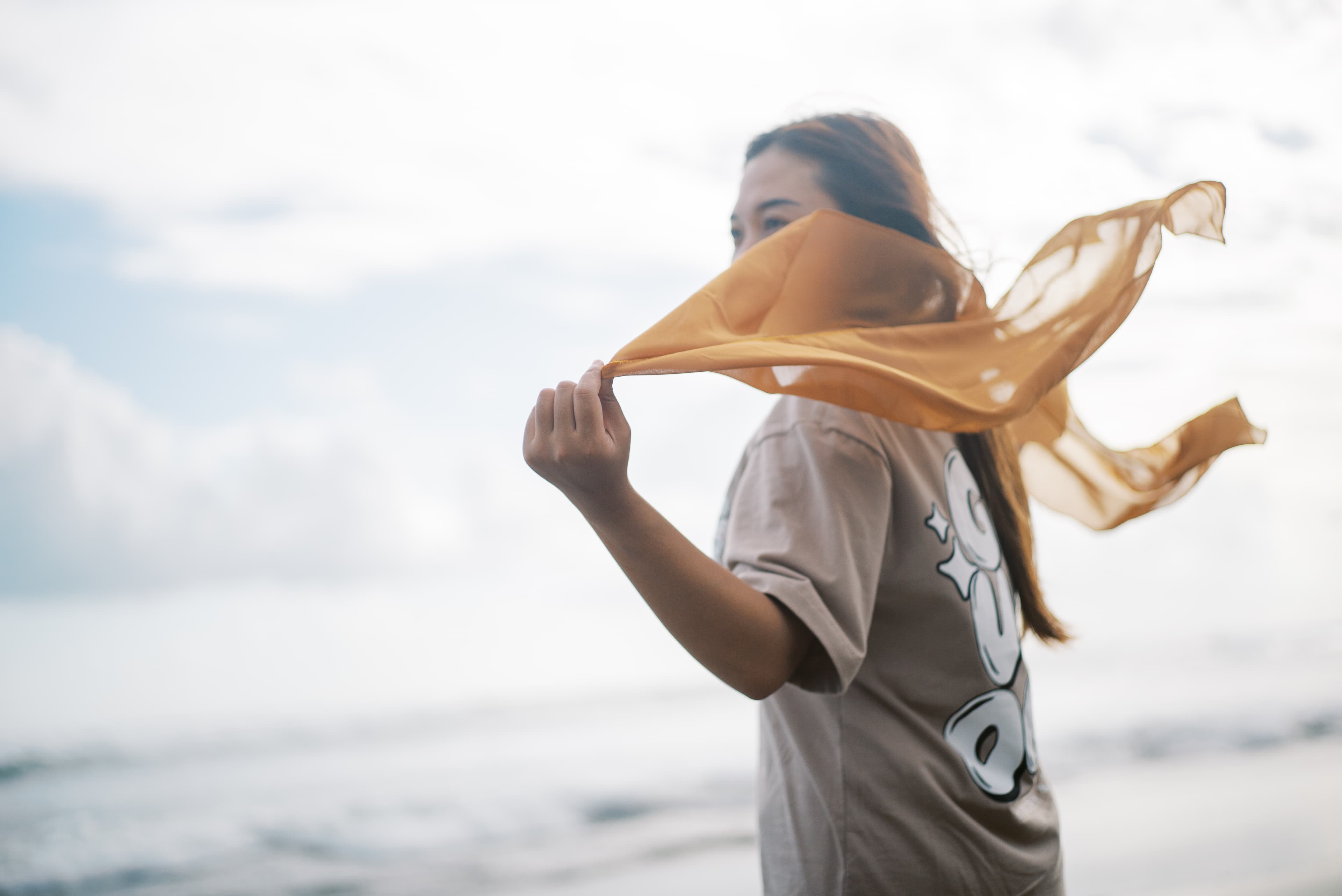 A young girl holds a scarf behind her as it blows in the wind.