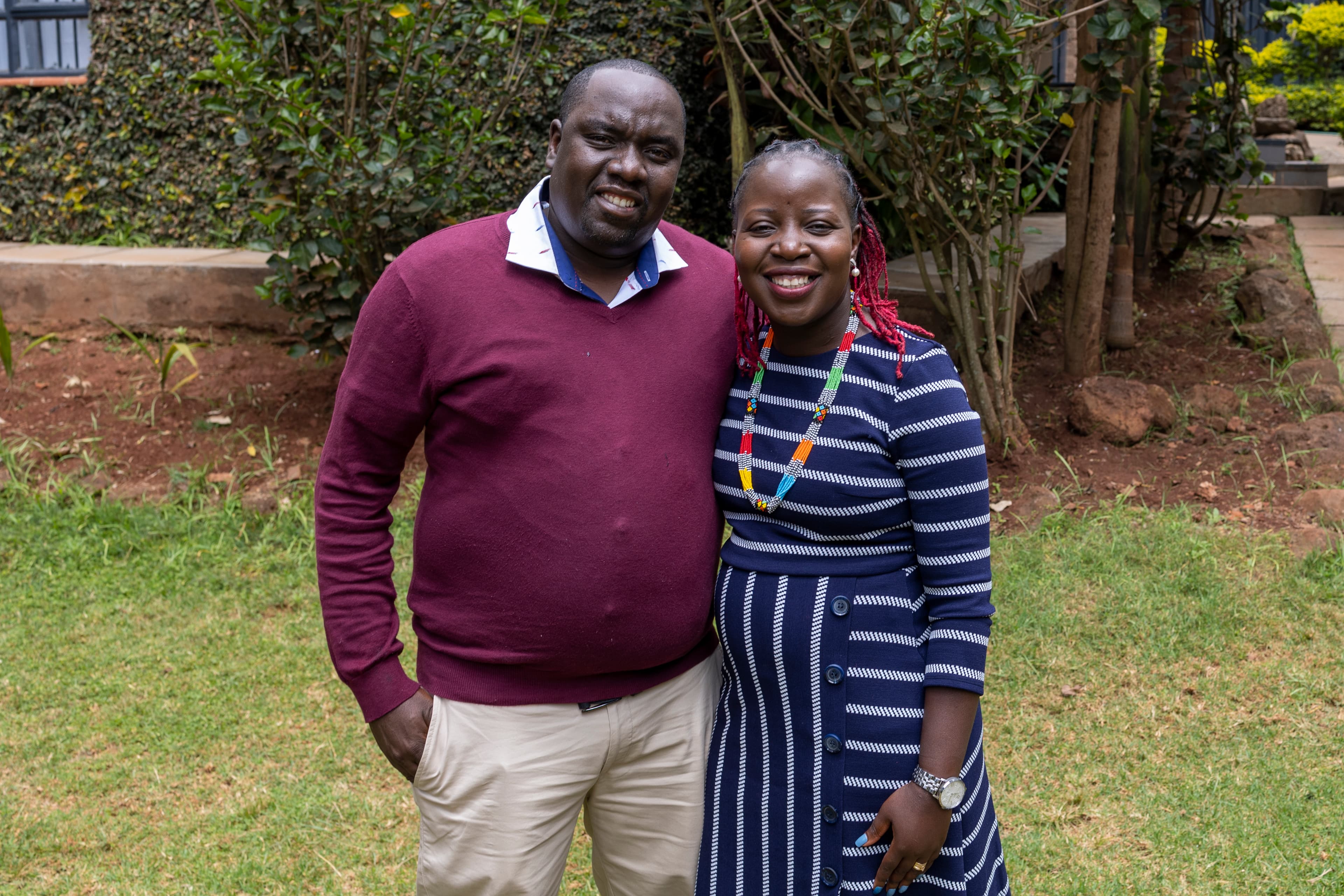 A husband and wife are standing together smiling at the camera.
